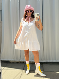 Person taking a mirror selfie wearing a white dress, yellow rain boots, and a pink hat.